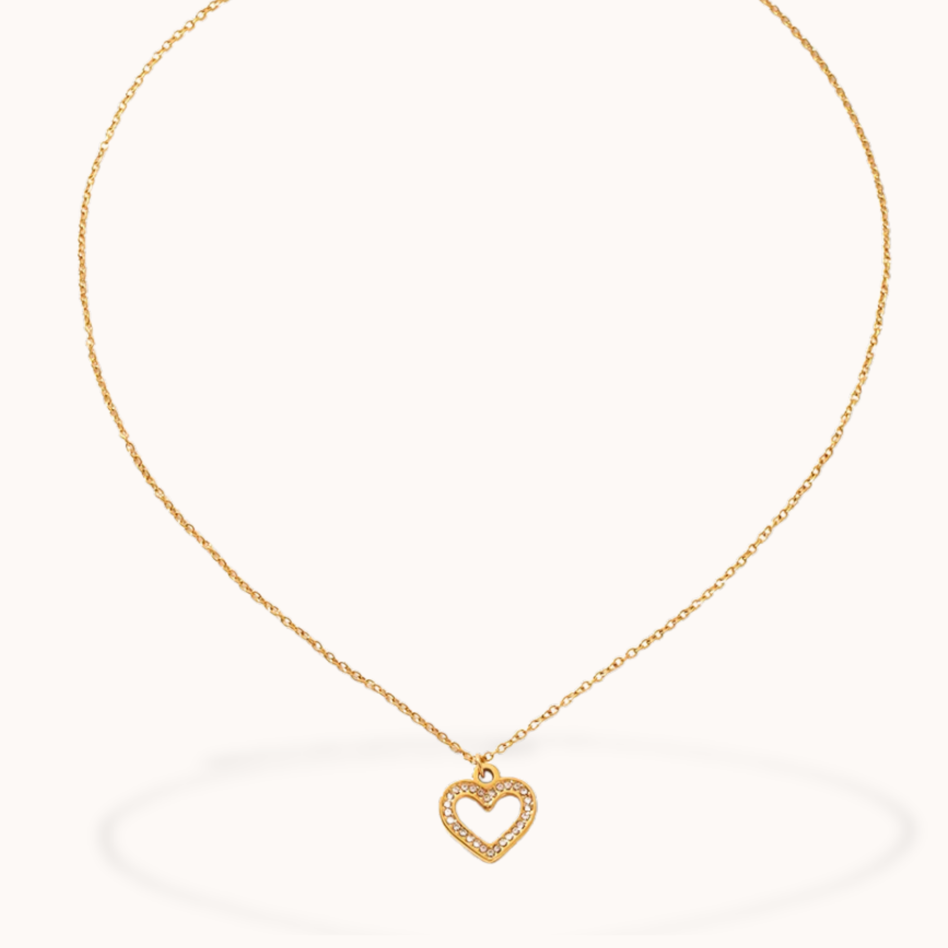 Gold necklace with a heart-shaped pendant on a white background