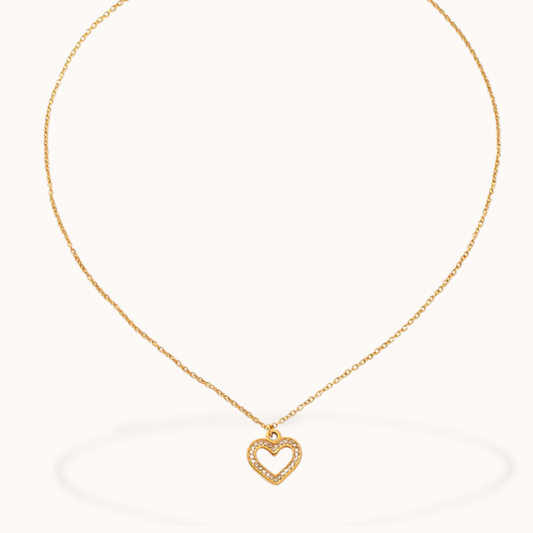 Gold necklace with a heart-shaped pendant on a white background