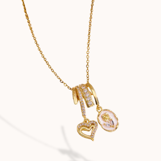 Gold necklace with heart and round pendant on a white background