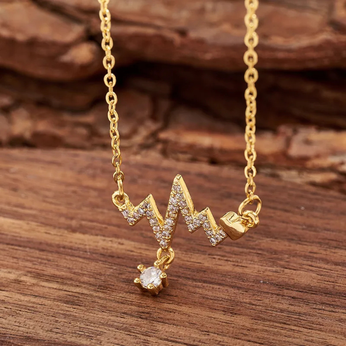 Gold necklace with a unique pendant on a wooden surface