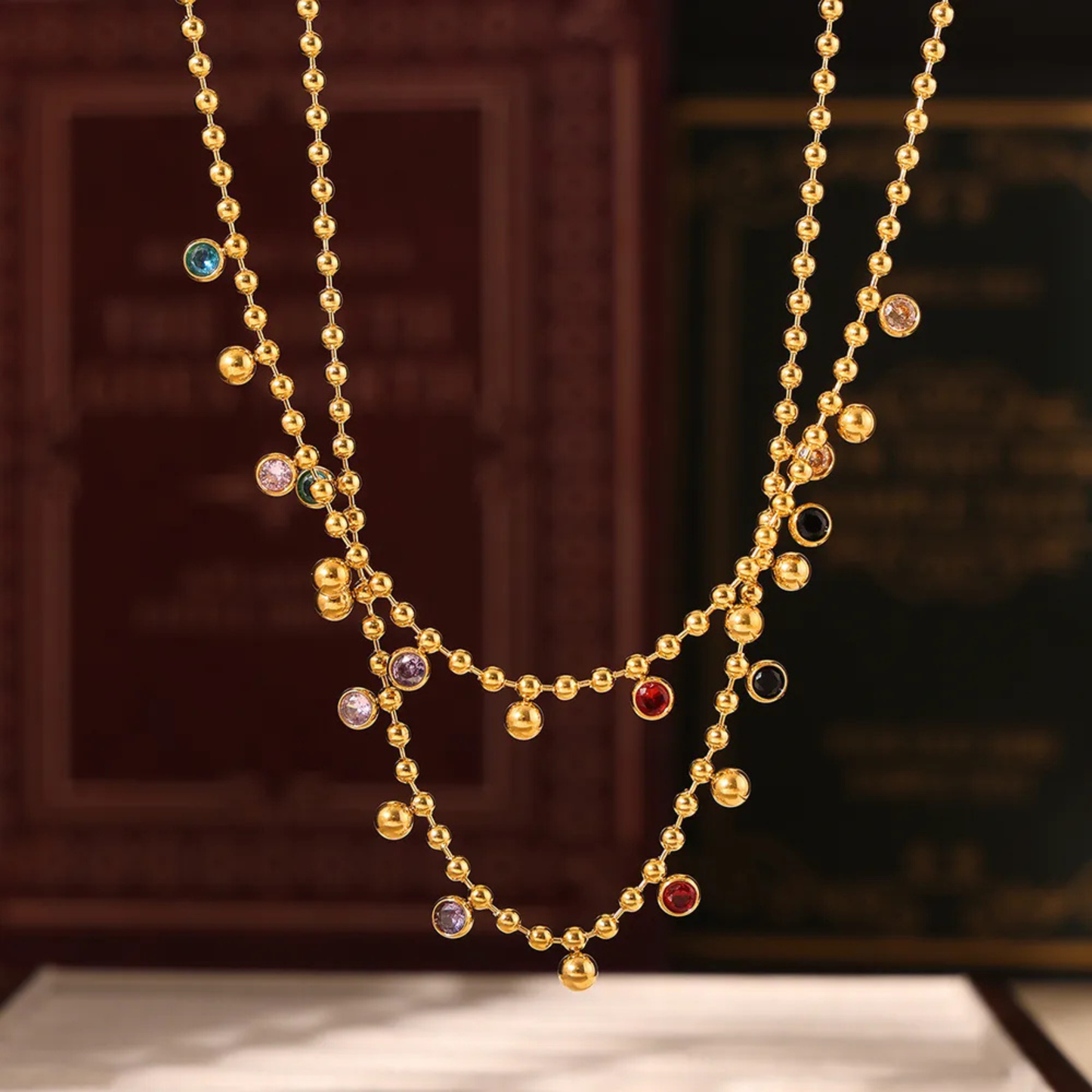 Gold beaded necklace with colored beads on a dark background