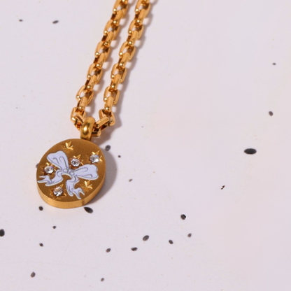 Gold necklace with a round pendant featuring a white design on a light background