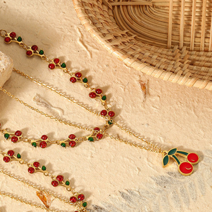Gold necklace with red and green accents on a textured surface