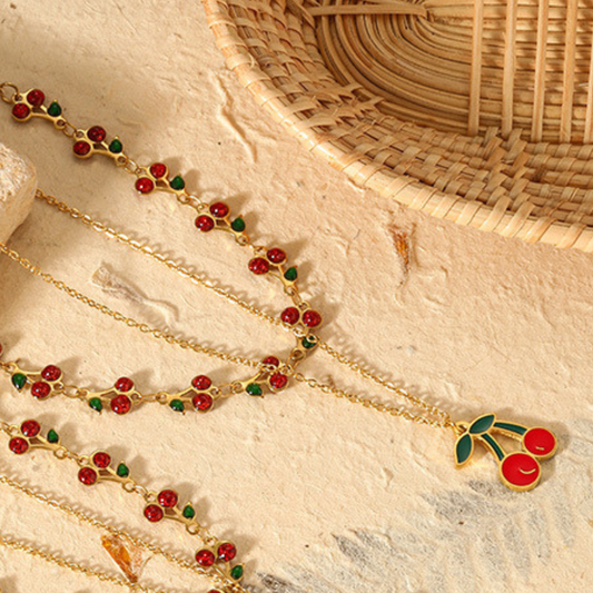 Gold necklace with red and green accents on a textured surface