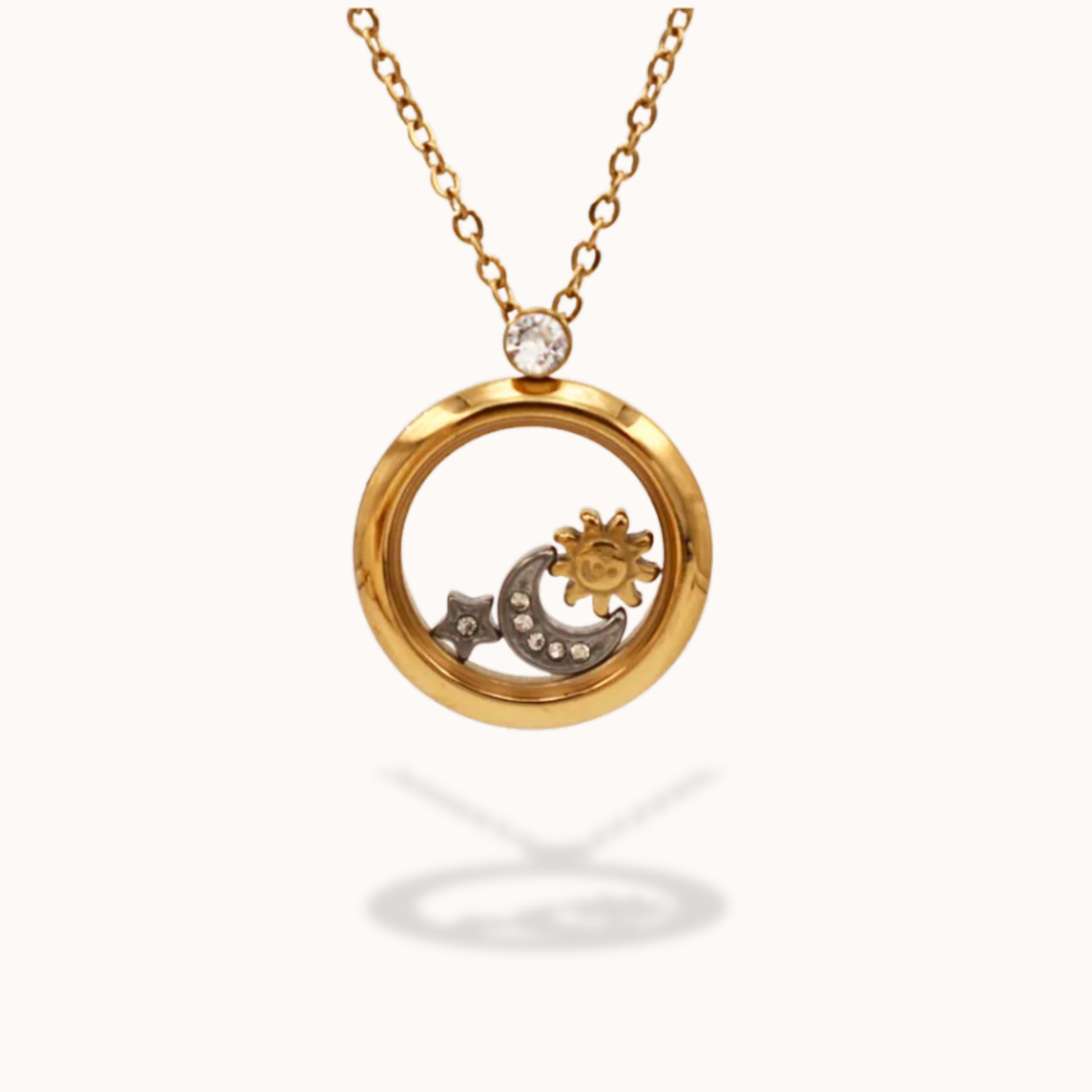 Gold necklace with a circular pendant featuring a sun and moon design on a white background