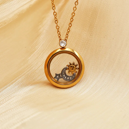 Gold necklace with a circular pendant featuring moon and sun designs on a beige fabric background