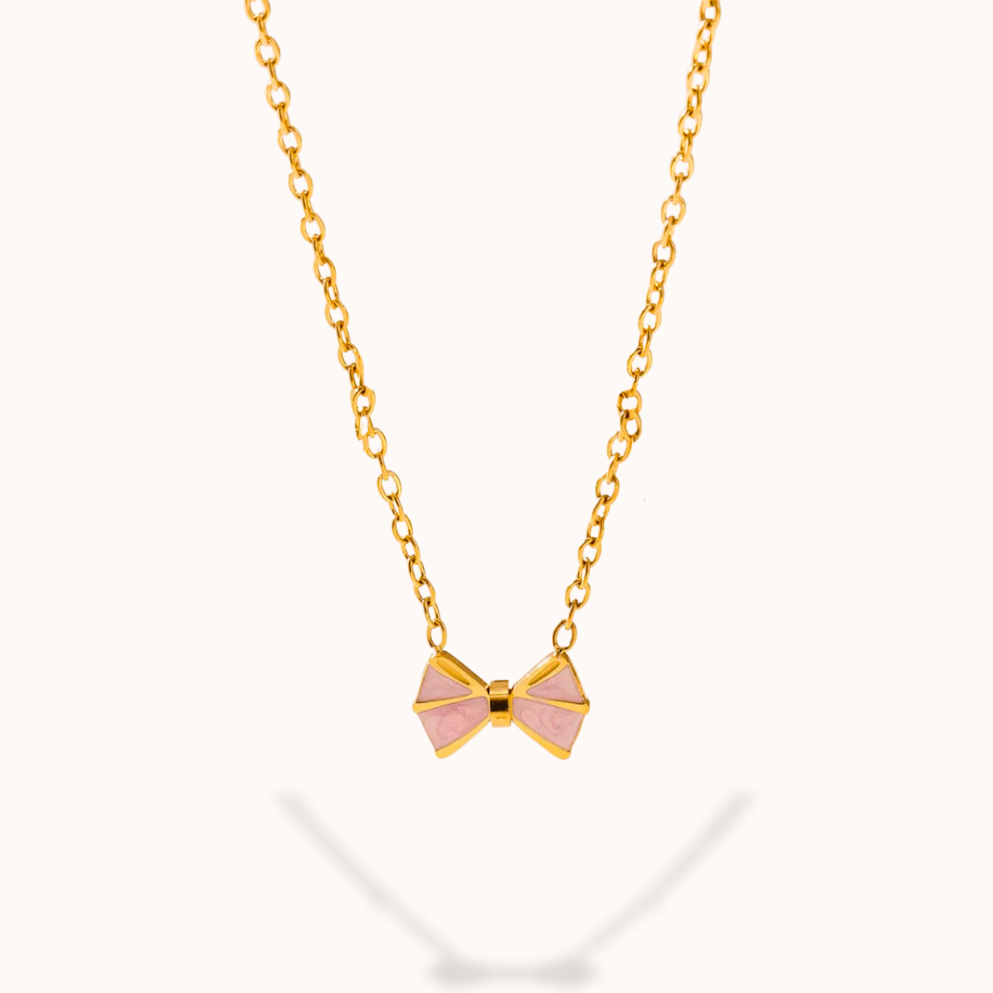 Gold necklace with a pink bow pendant on a white background
