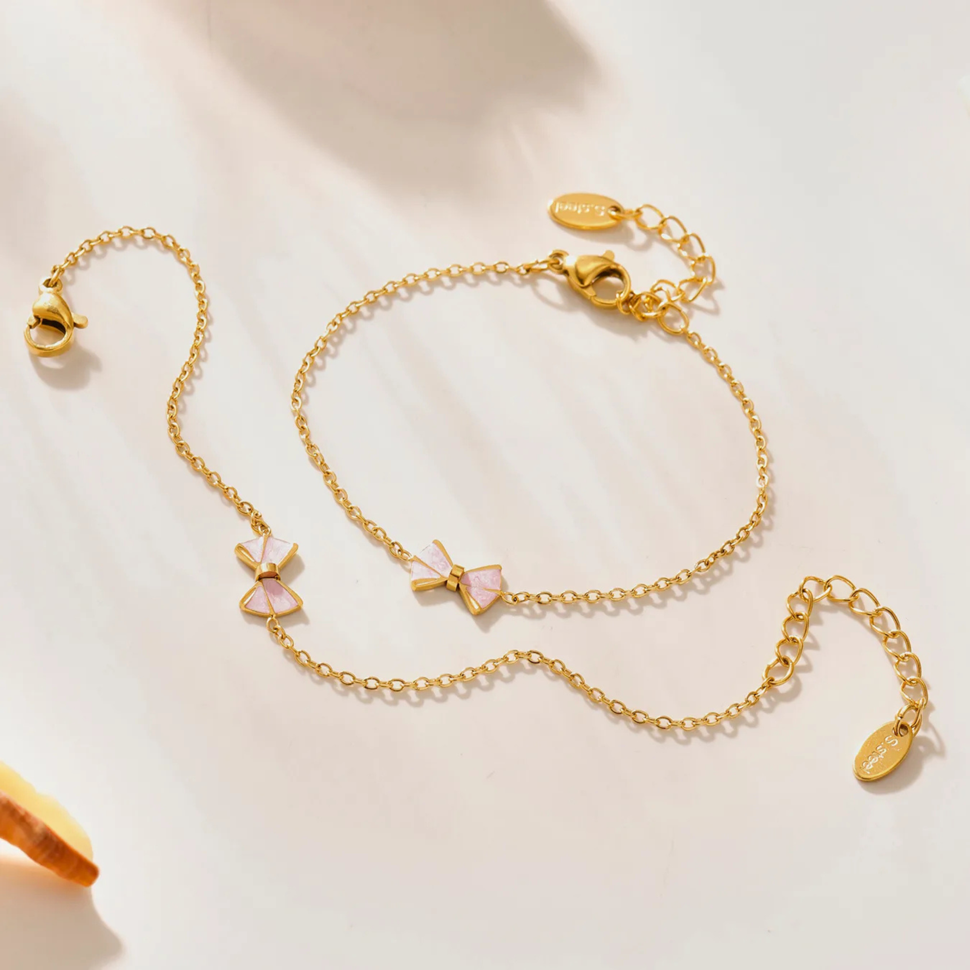 Gold bracelet with heart-shaped charms on a light background