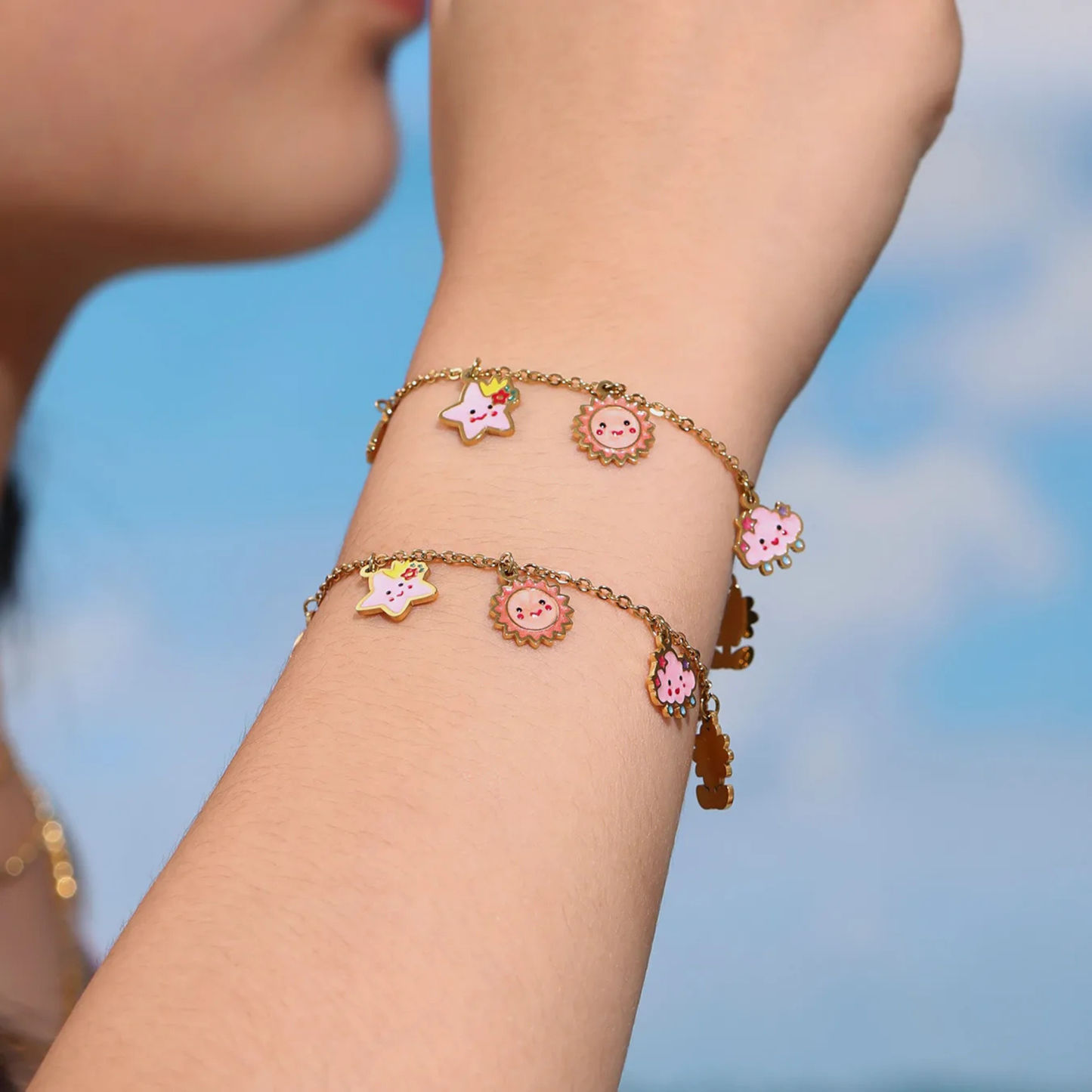 Bracelet with cartoon character charms on a wrist against a blurred blue sky background