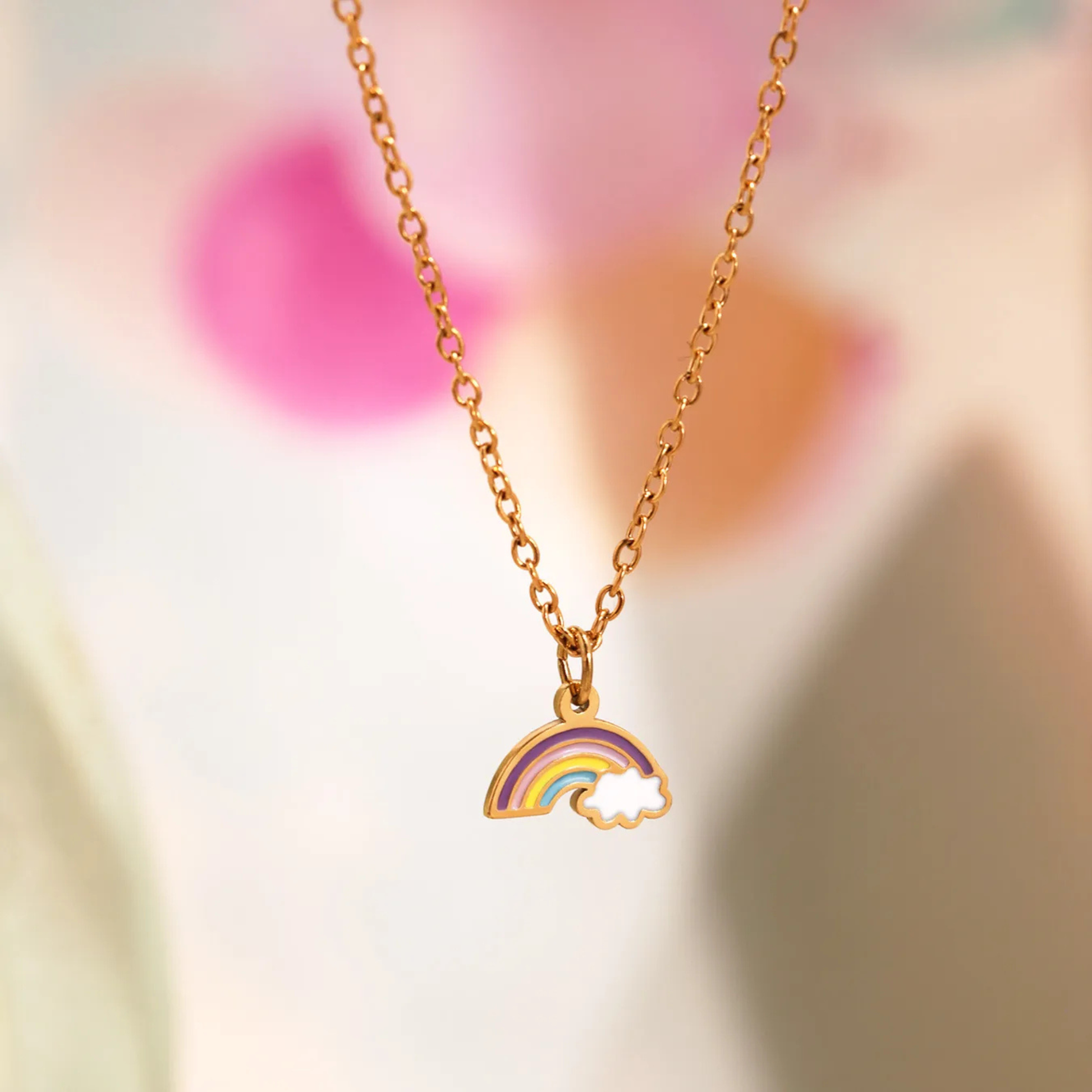Gold necklace with a rainbow pendant on a blurred background