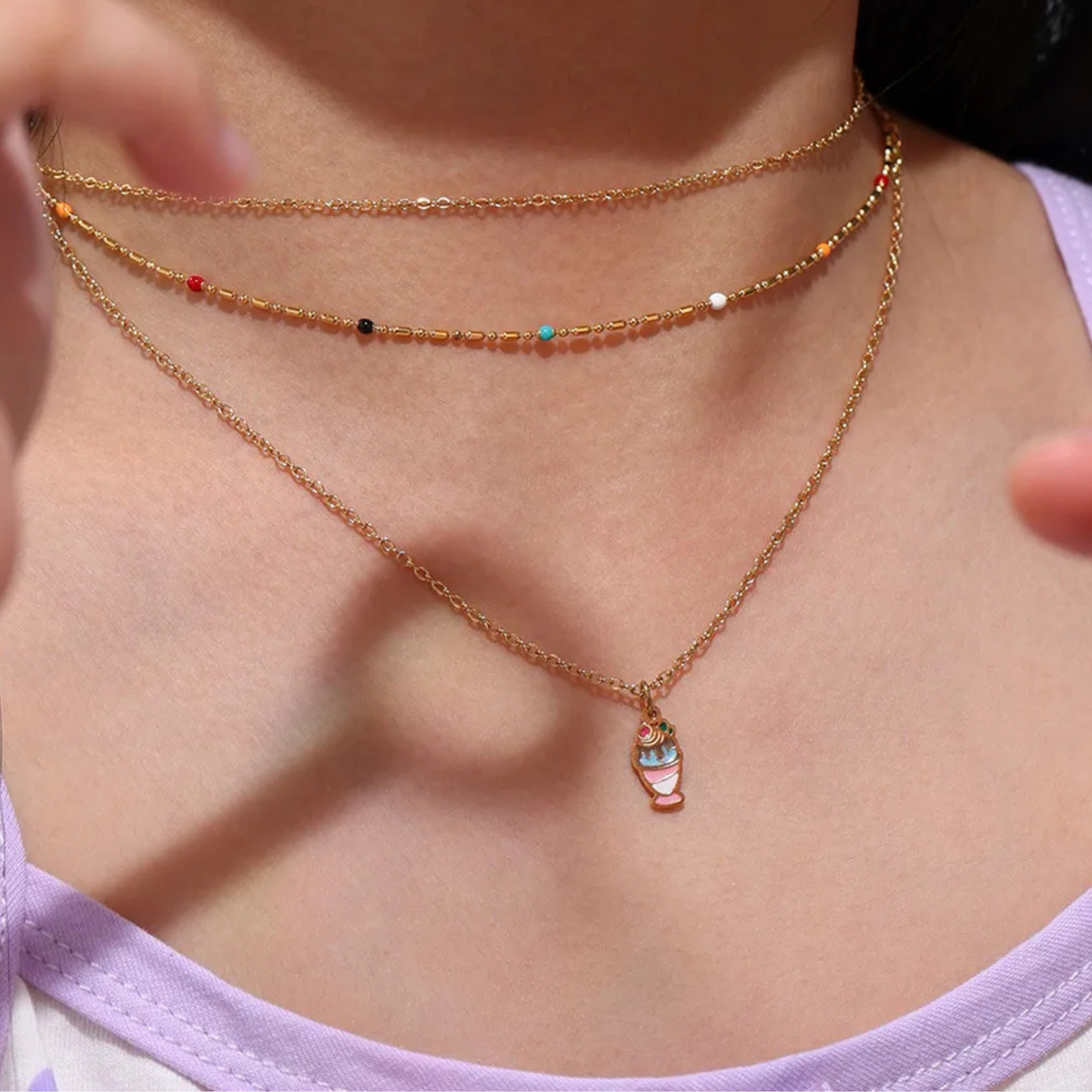 Close-up of a person wearing a gold necklace with a small pendant.