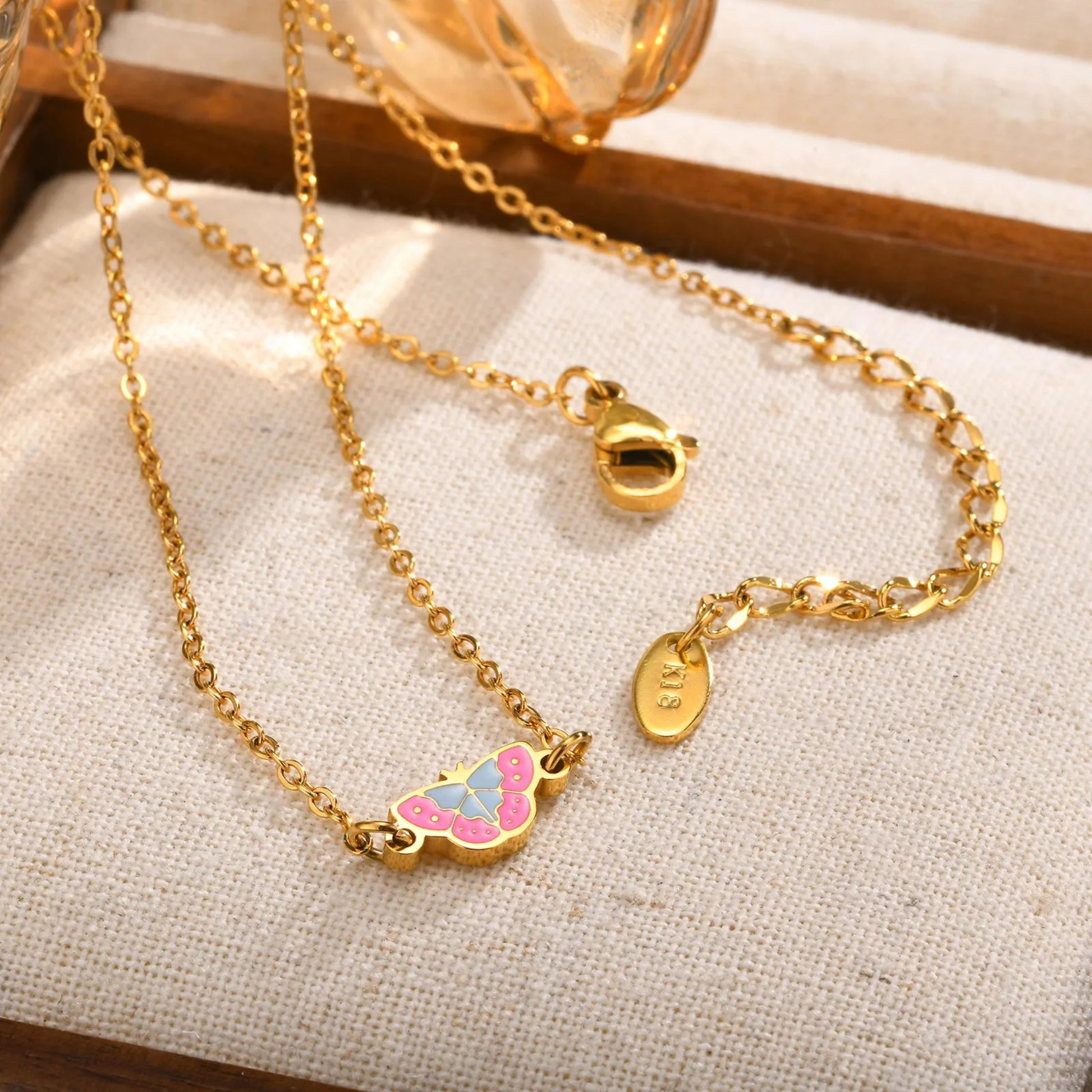 Gold necklace with butterfly pendant on a textured surface