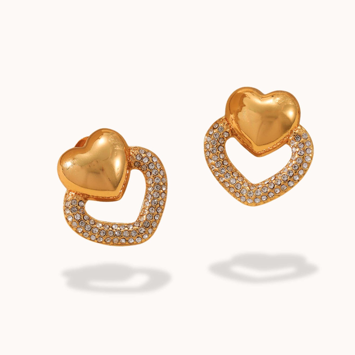 Gold heart-shaped earrings with diamond accents on a white background