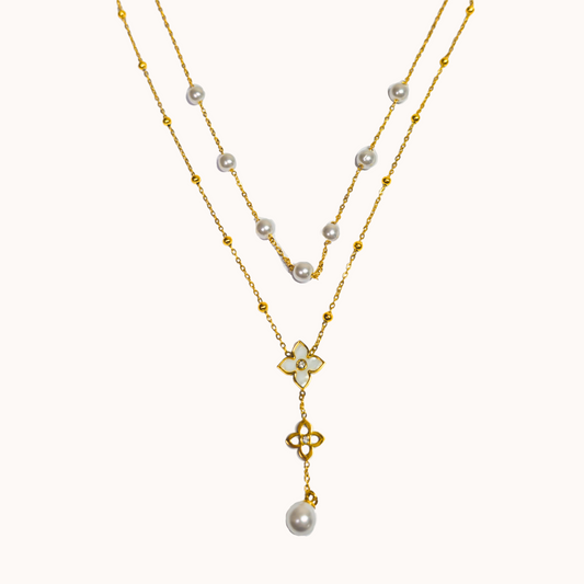 Two-layered necklace with pearls and a floral pendant on a white background