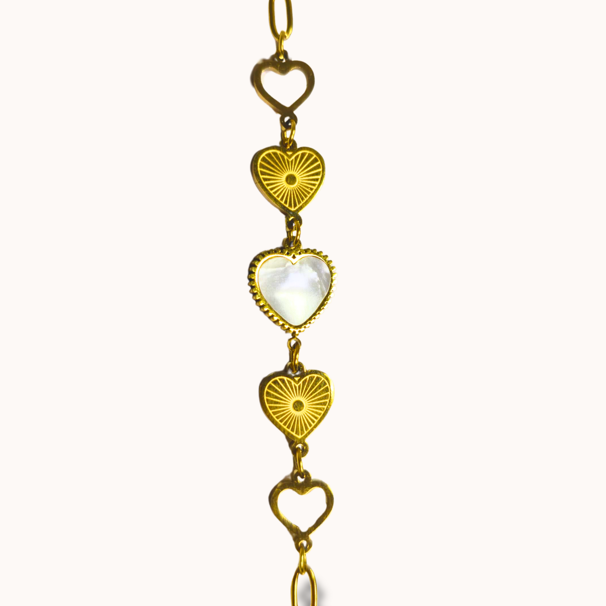 Gold necklace with heart and sunburst designs on a white background