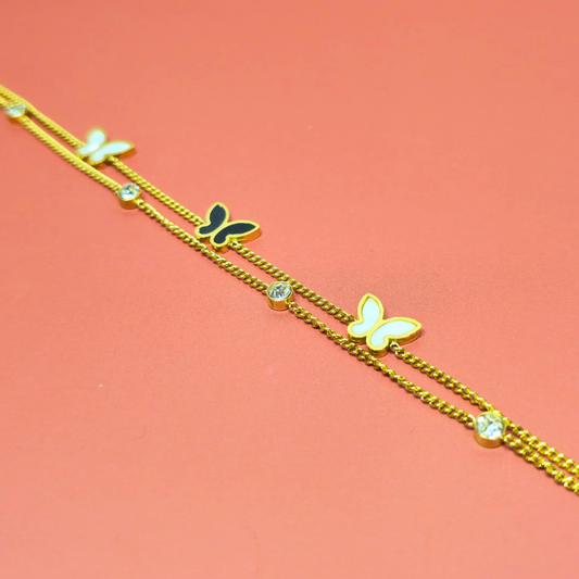Gold bracelet with butterfly charms on a pink background