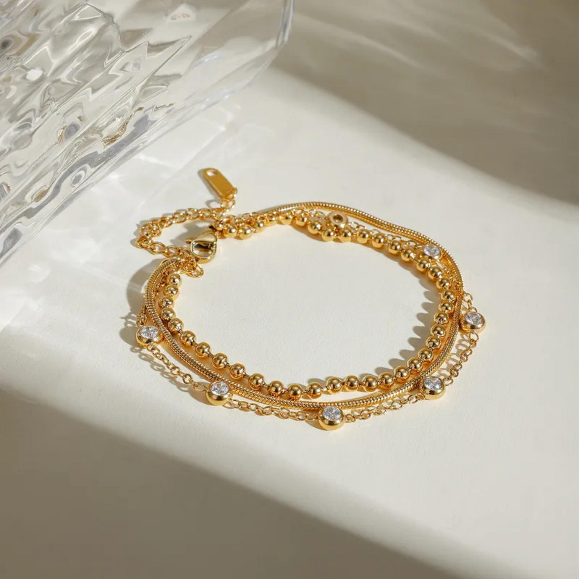 Gold bracelet with chain and bead details on a light surface