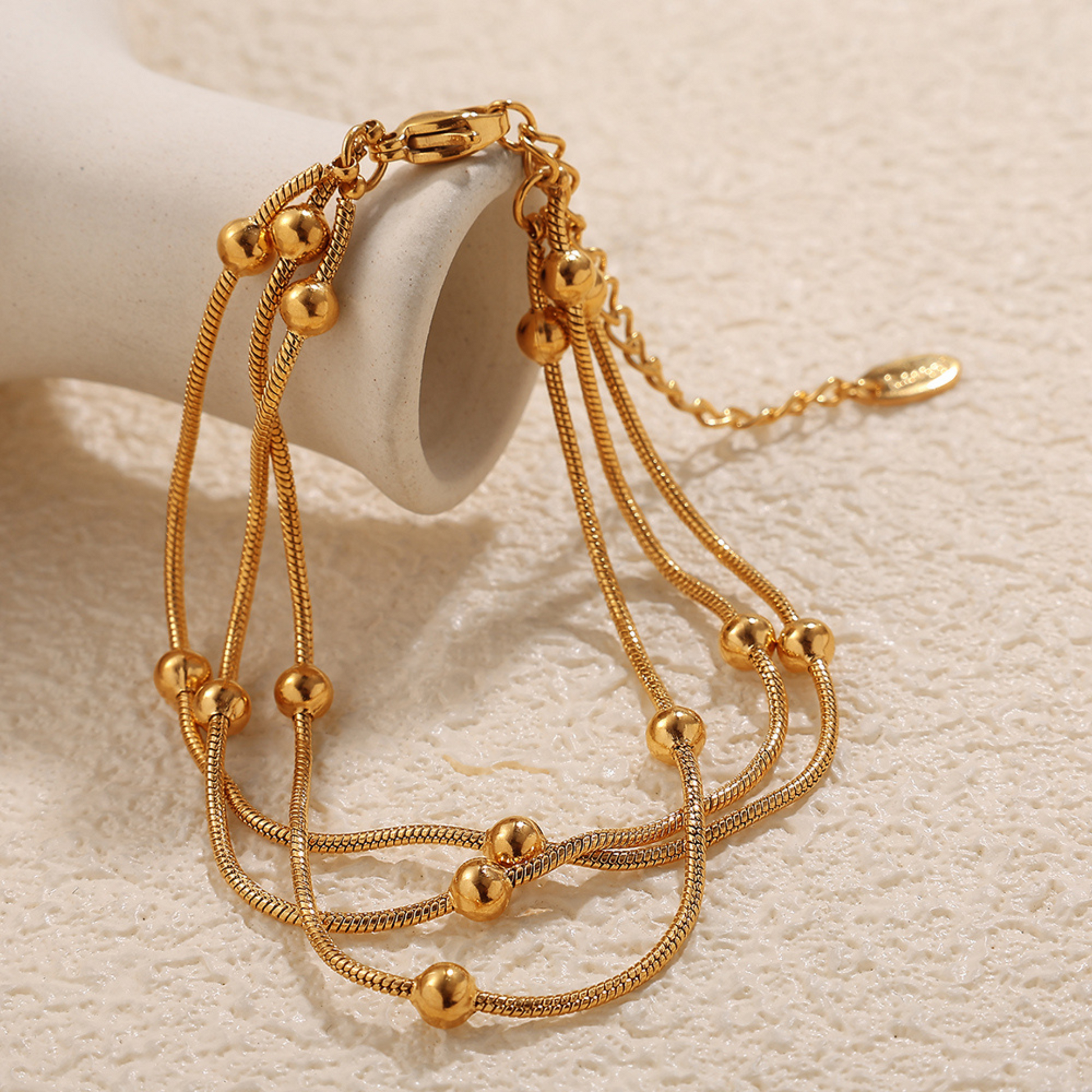 Gold bracelet with spherical beads on a beige background