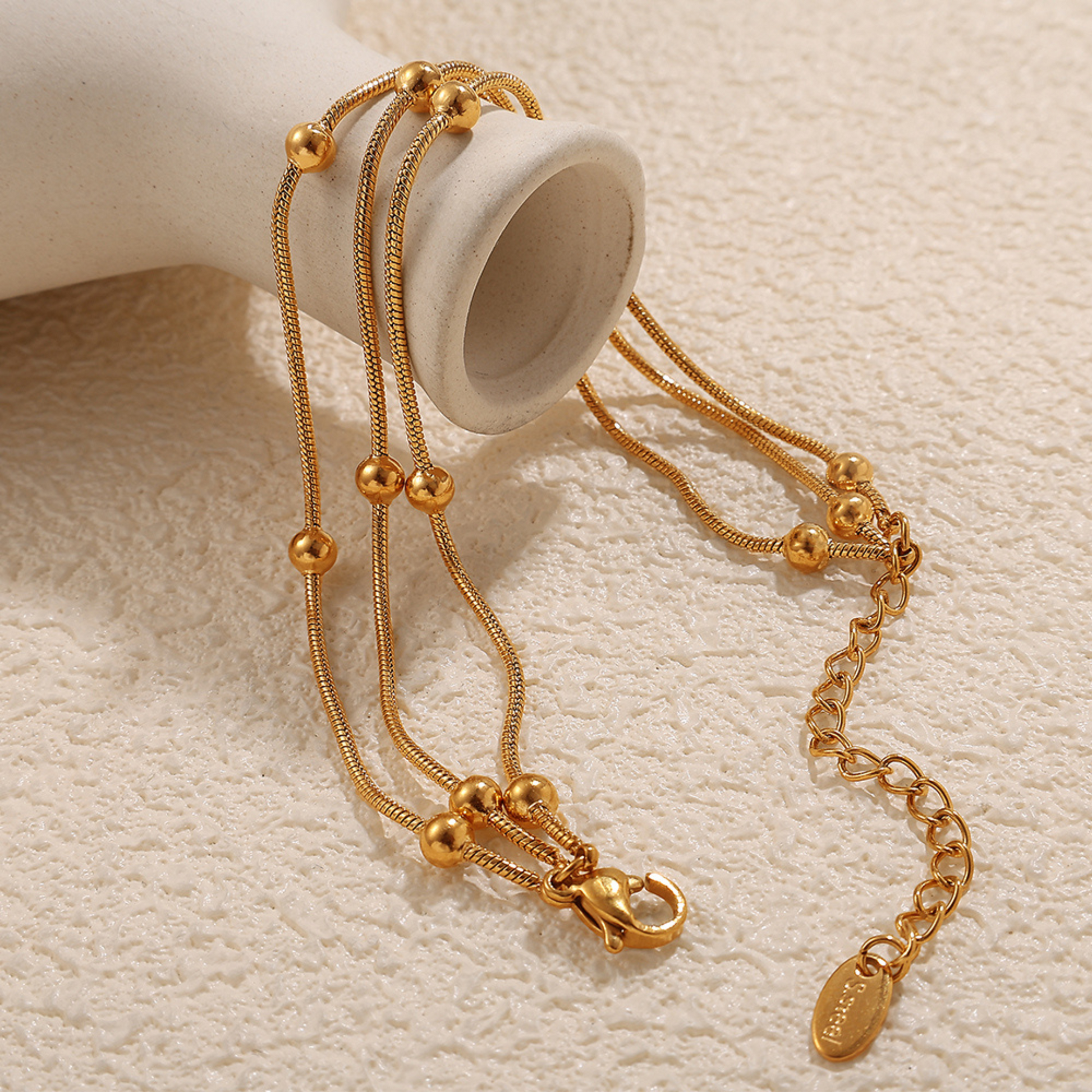 Gold necklace with multiple chains on a textured beige surface