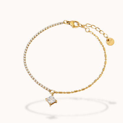Gold bracelet with a diamond-shaped charm on a white background