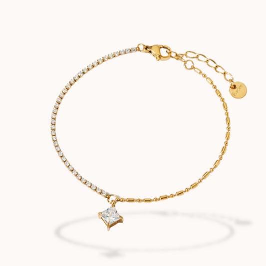 Gold bracelet with a diamond-shaped charm on a white background