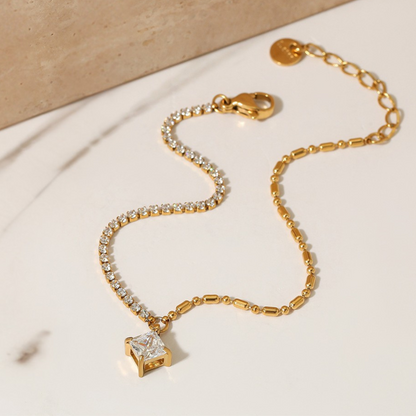 Gold bracelet with diamond charm on a beige background