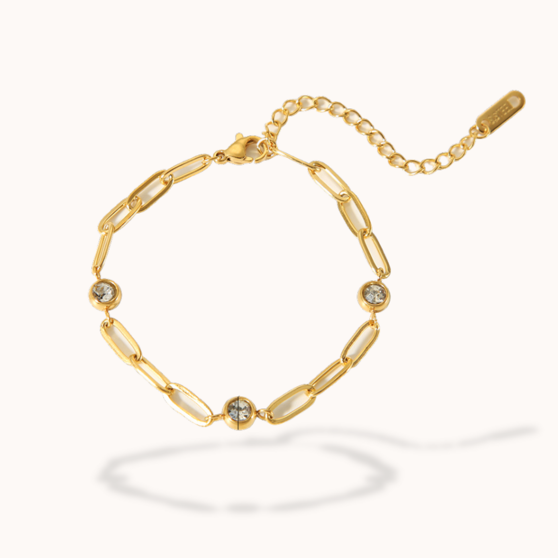 Gold bracelet with chain links and small gemstones on a white background