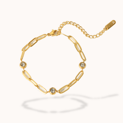 Gold bracelet with chain links and small gemstones on a white background