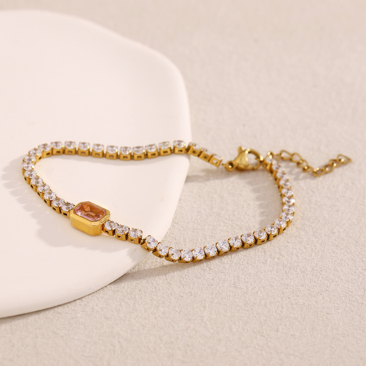 Gold bracelet with pink gem stones on a beige background