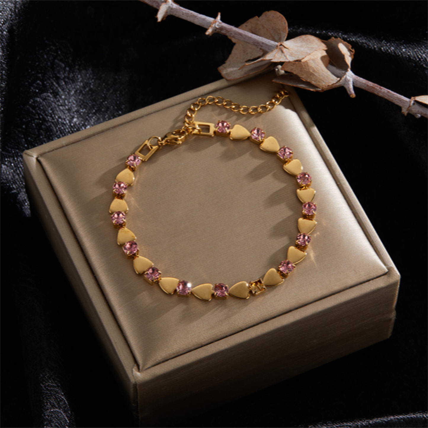 Gold bracelet with diamond accents on a beige jewelry box against a dark background