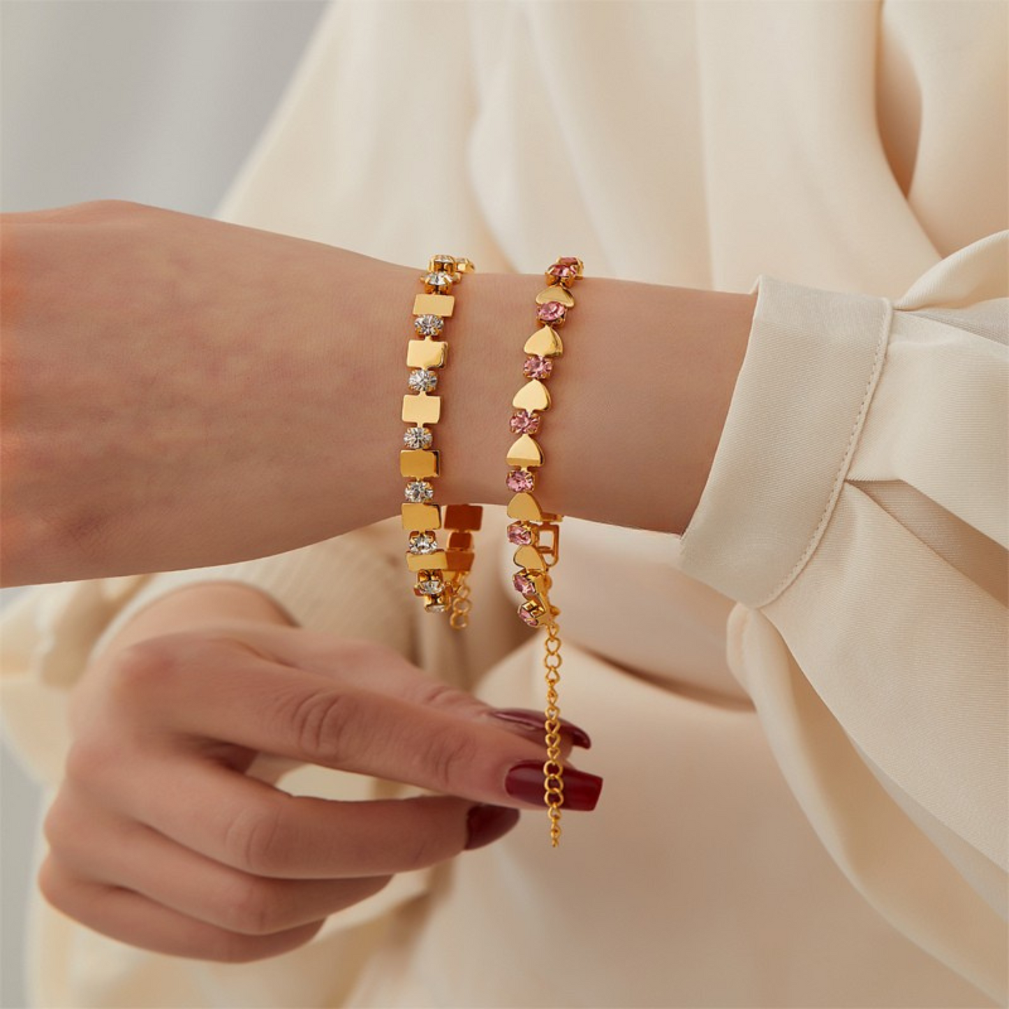 Two gold bracelets on a wrist with a neutral background