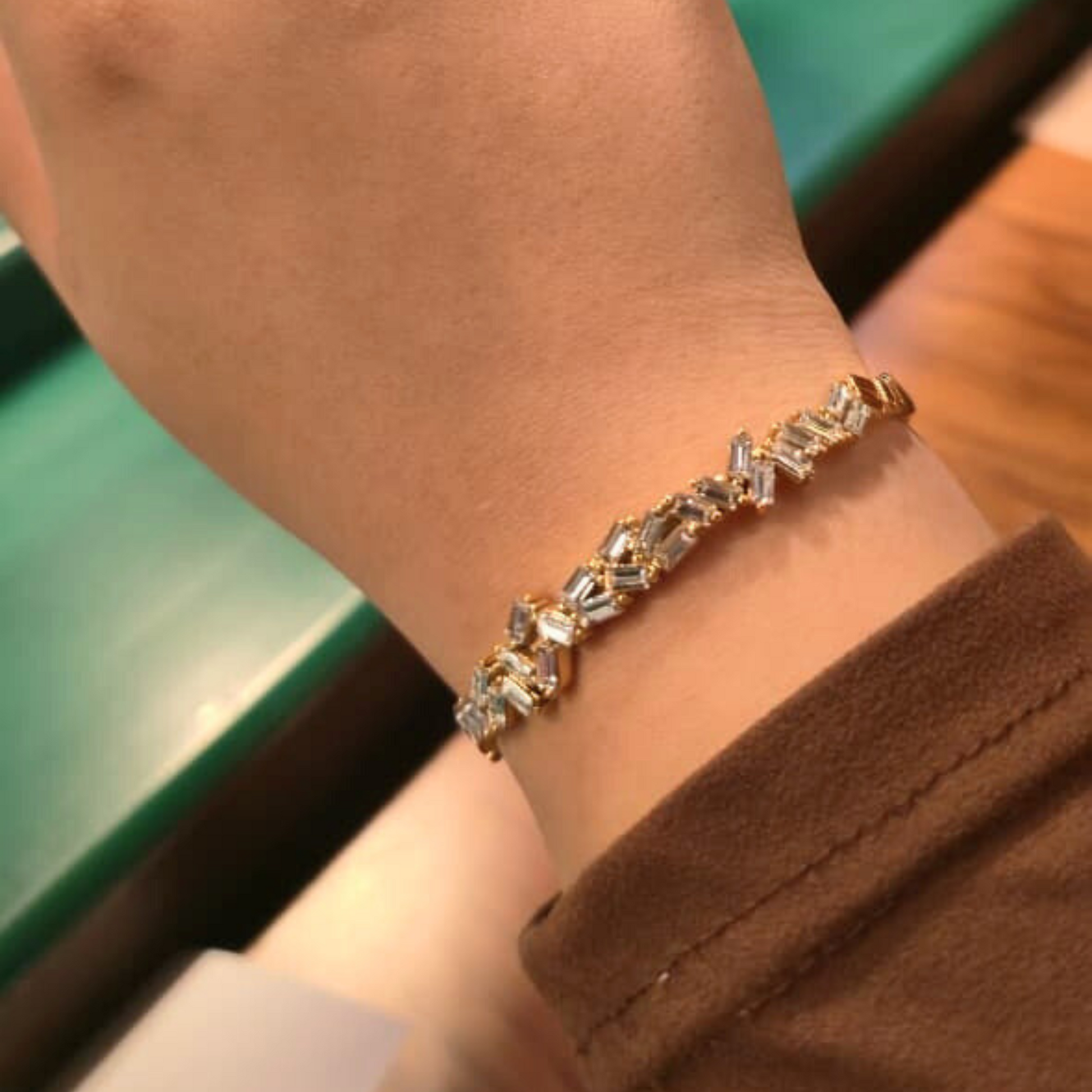 Gold bracelet with clear stones on a wrist, blurred background