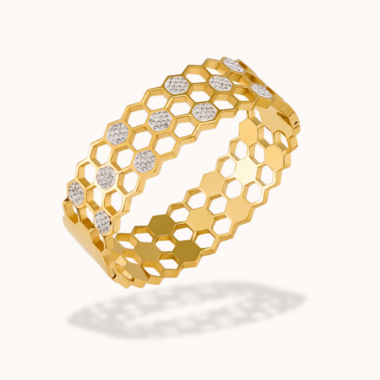 Gold bracelet with honeycomb design and embedded stones on a white background