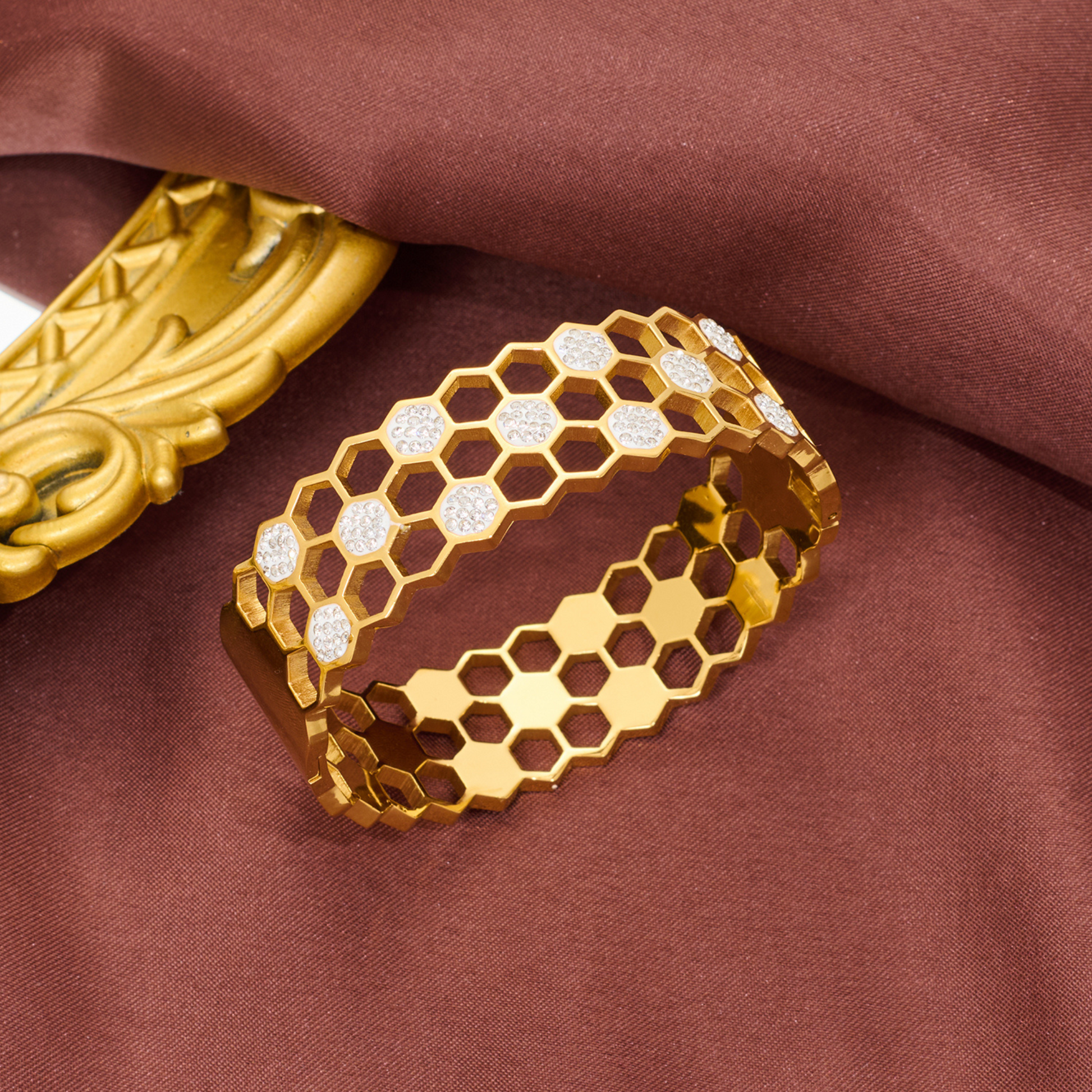 Gold bracelet with honeycomb pattern on a brown fabric background
