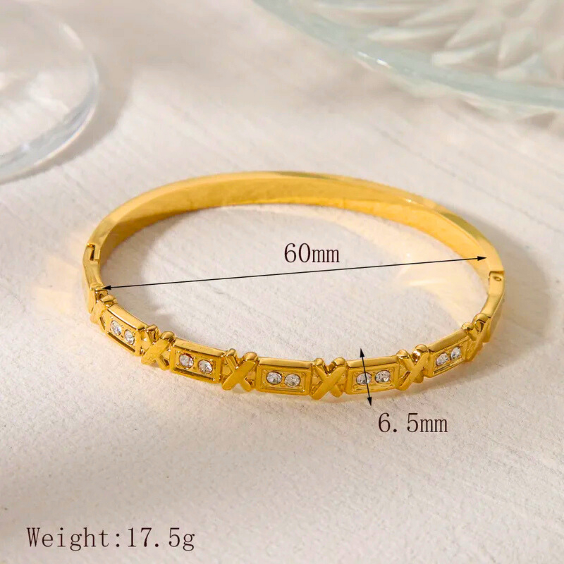 Gold bracelet with measurements and weight on a light background