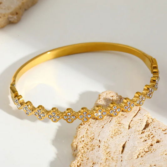 Gold headband with rhinestones on a textured beige surface
