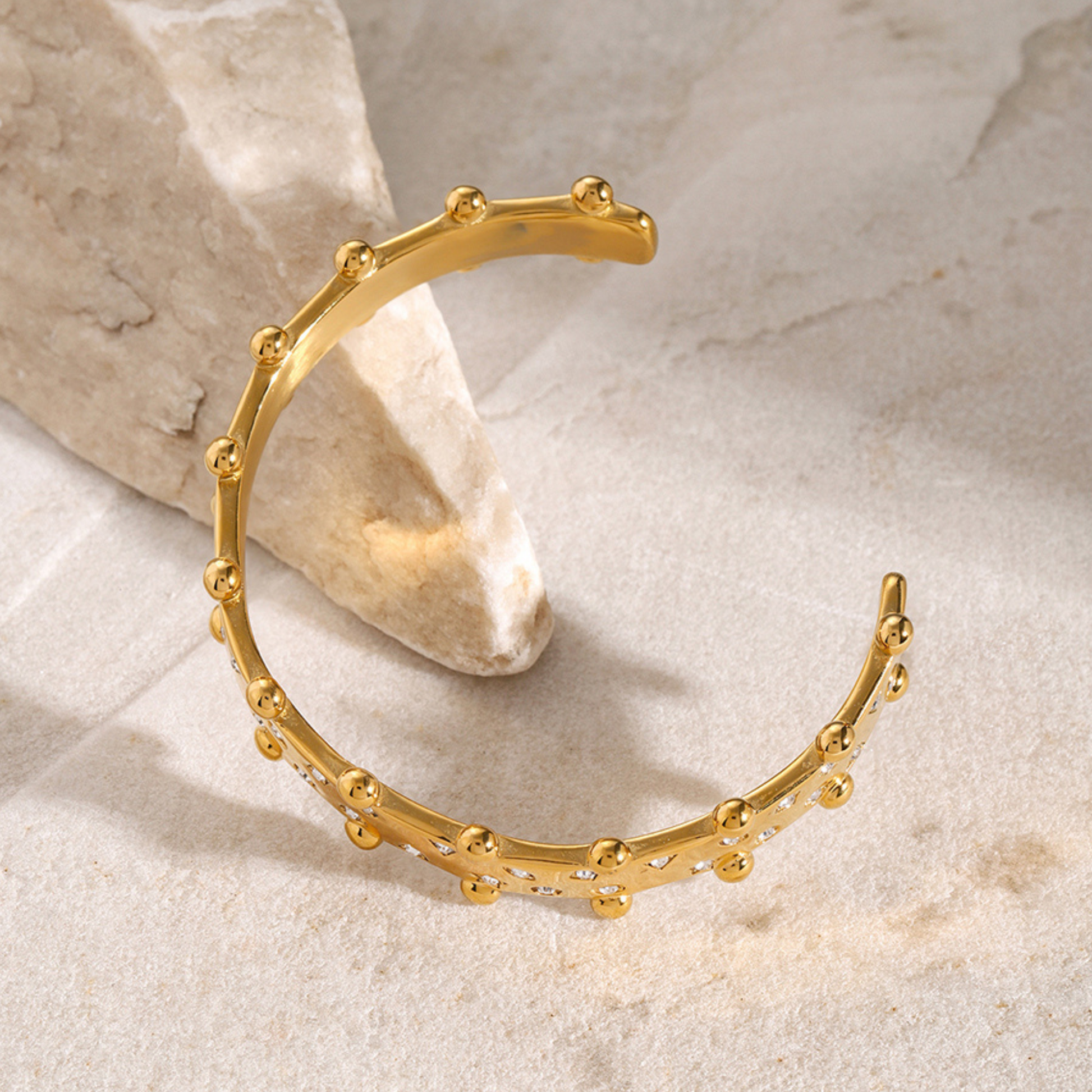 Gold bracelet on a textured beige surface