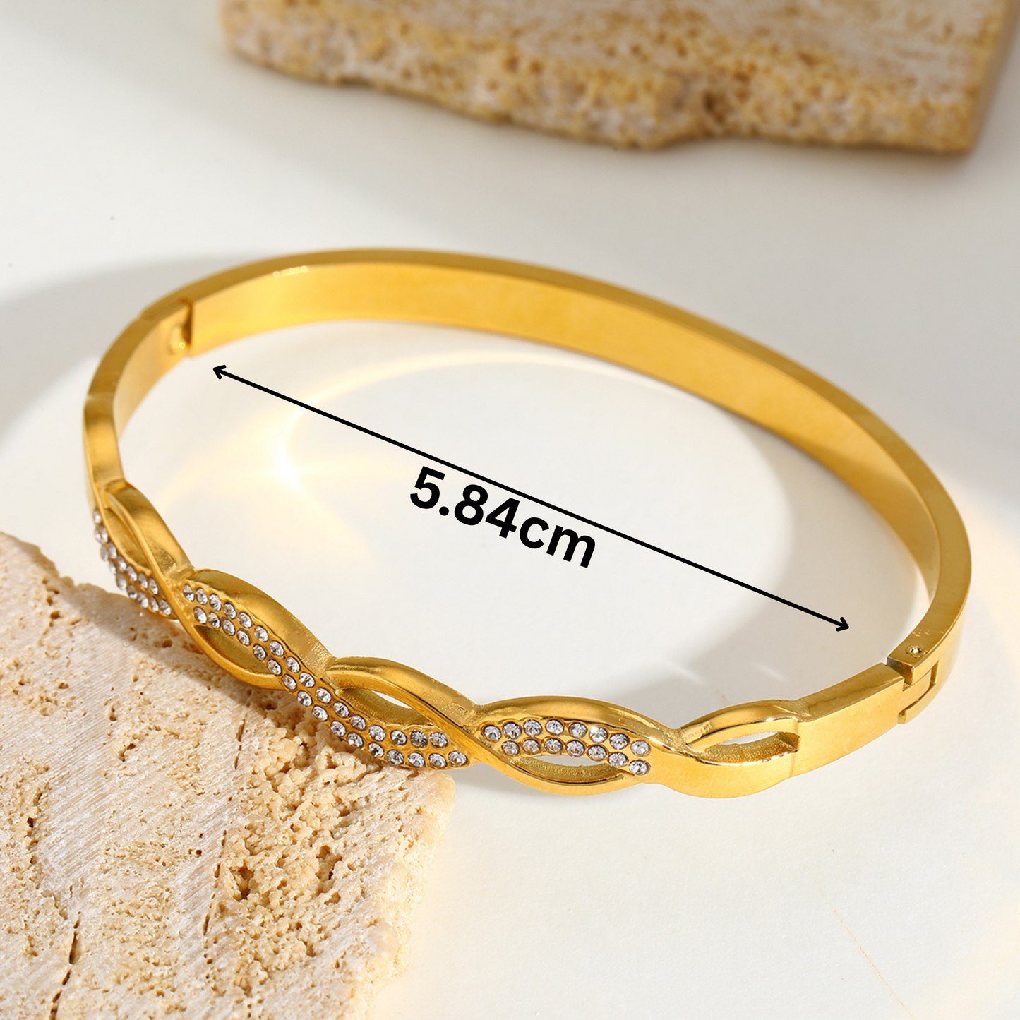 Gold bracelet with measurement details on a textured surface