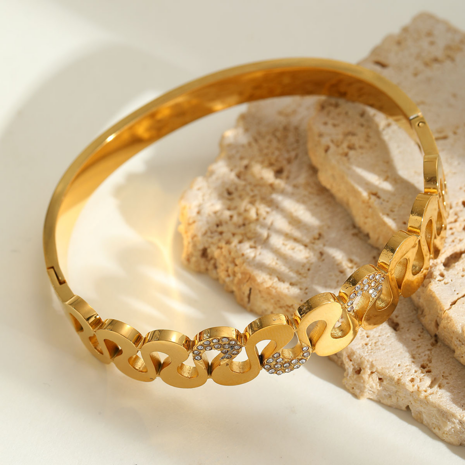 Gold bracelet with diamond accents on a textured beige surface