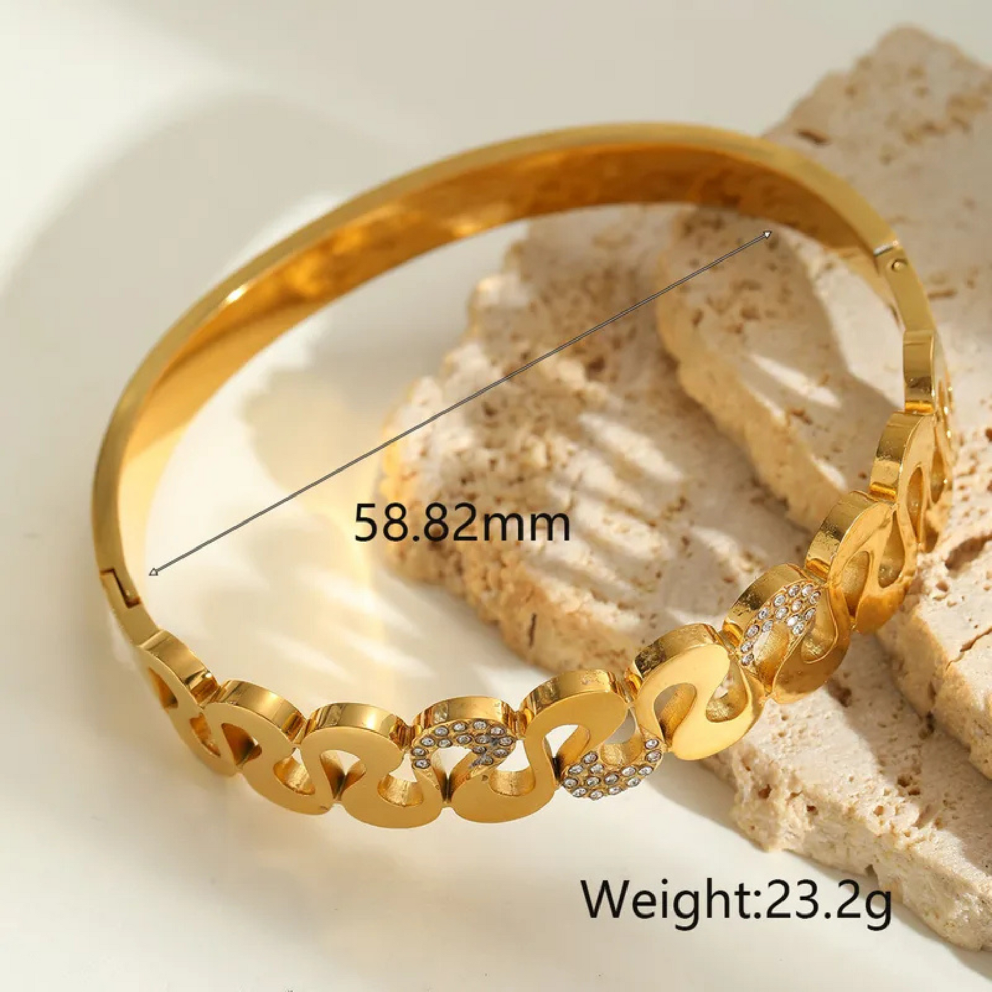 Gold bracelet with measurements and weight on a textured surface