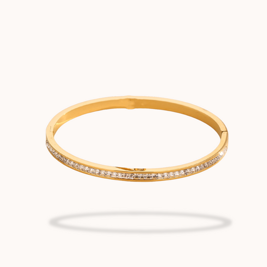 Gold bangle with small diamonds on a white background