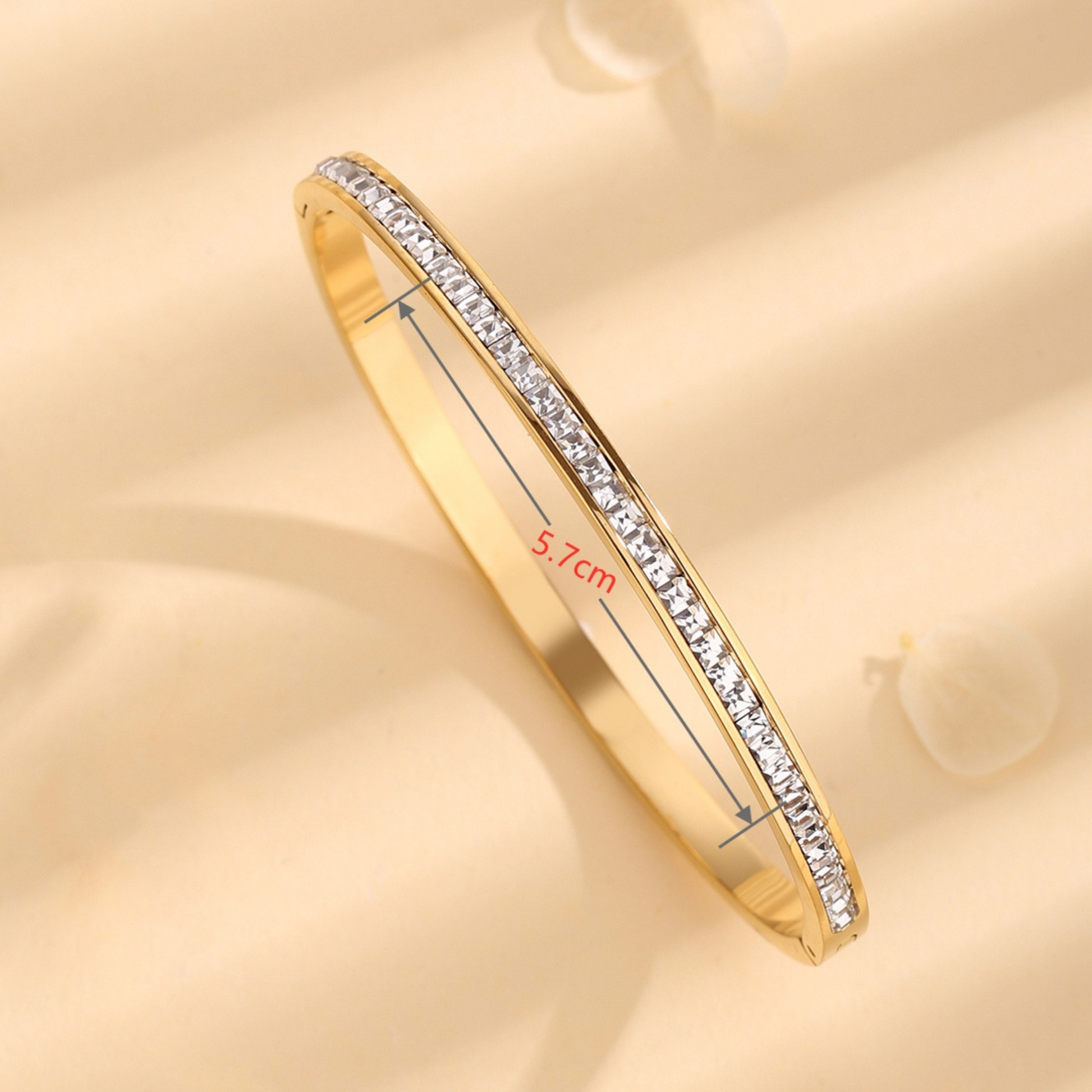 Gold bracelet with diamond accents on a beige background