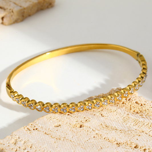 Gold bracelet with small stones on a light background