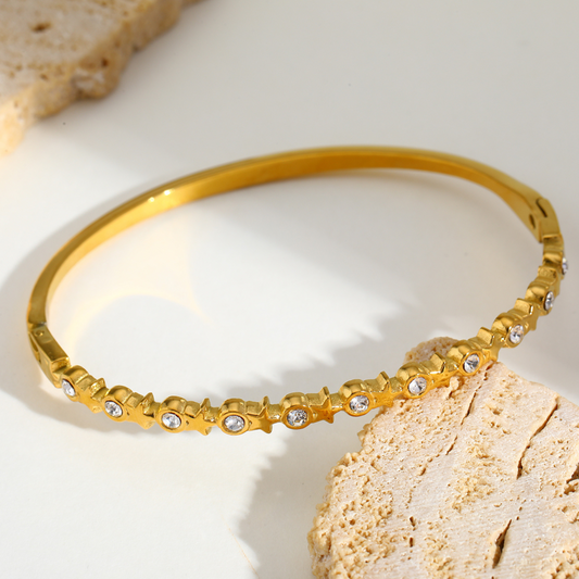 Gold bracelet with small stones on a light background
