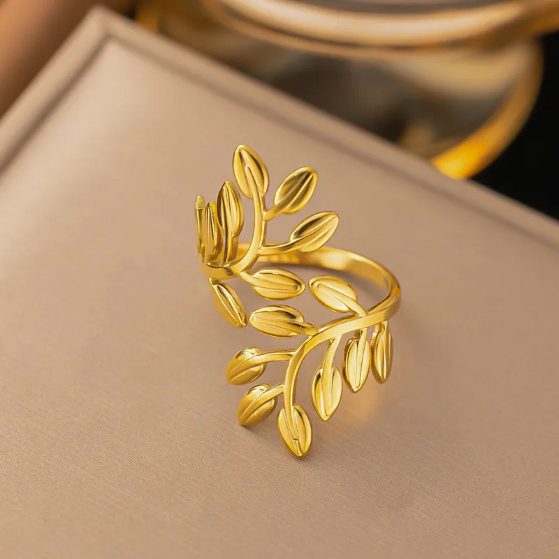 Gold leaf-shaped ring on a beige surface