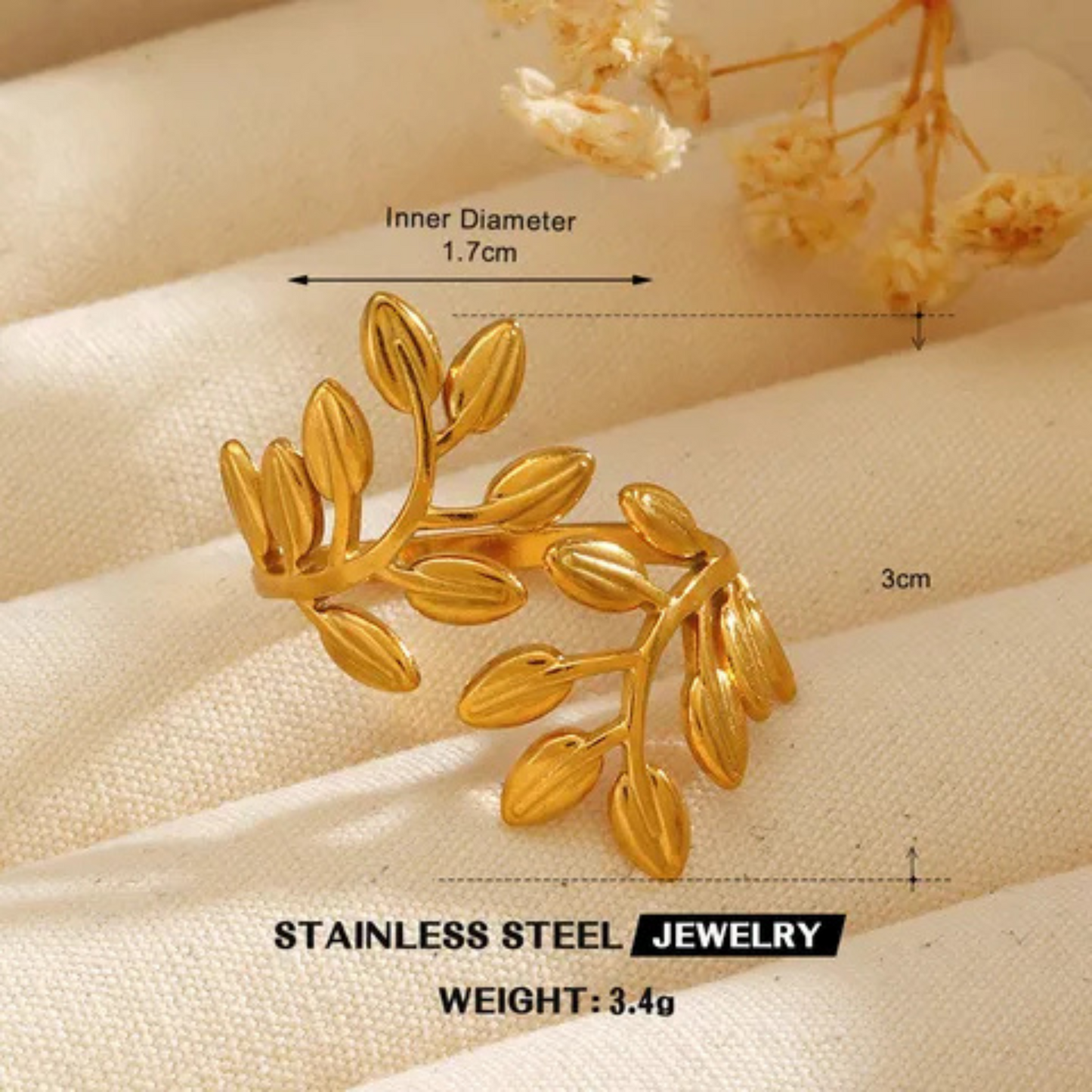 Gold leaf-shaped jewelry piece with measurements on a beige fabric background