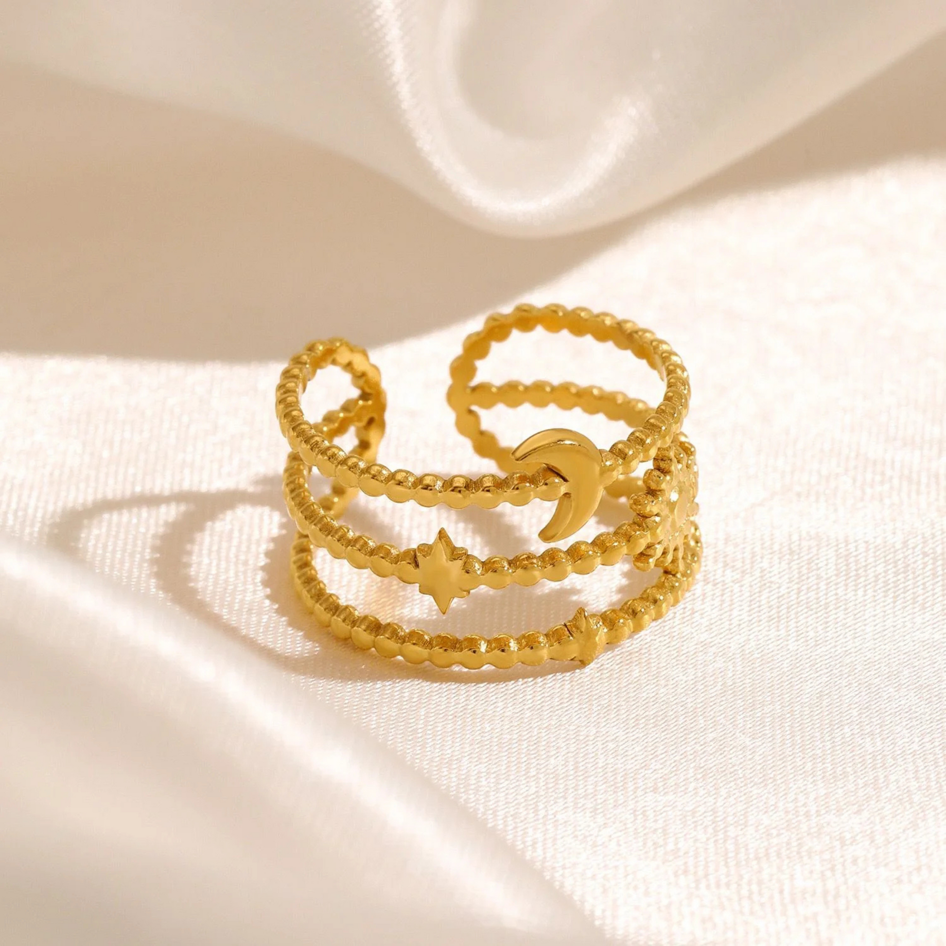 gold rings with star and moon designs on a beige fabric background