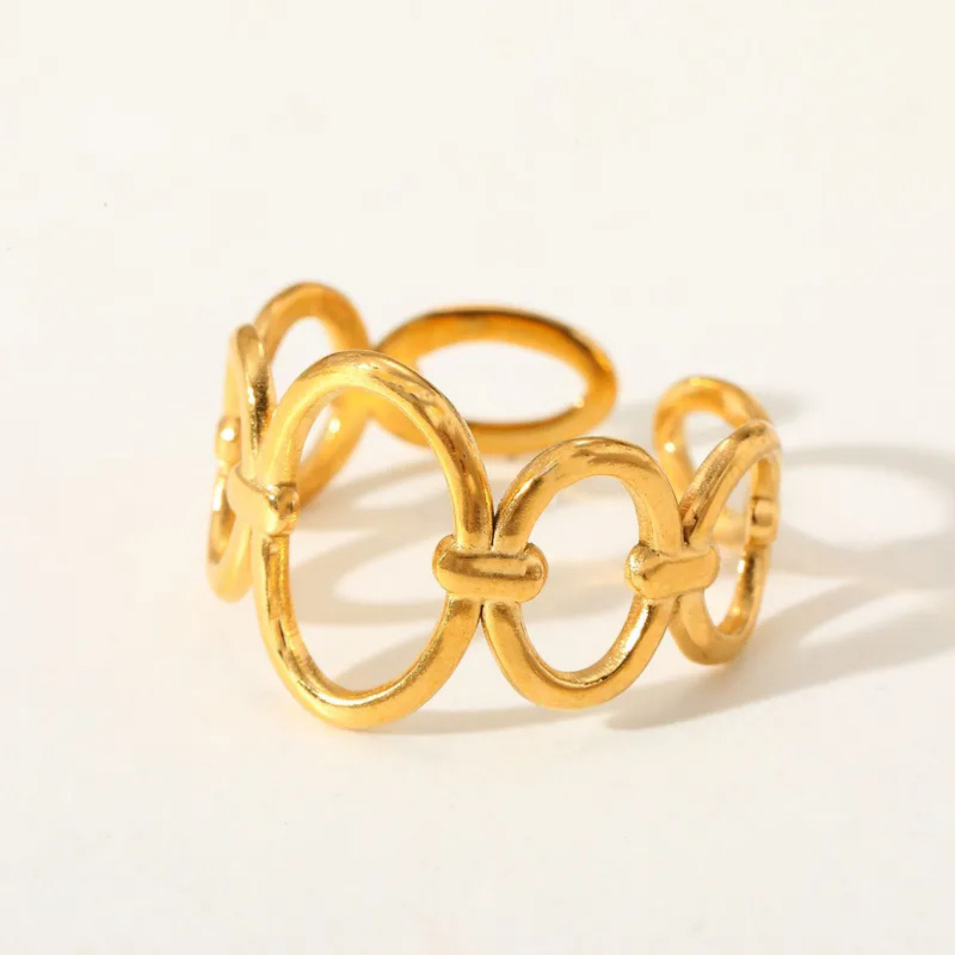 Gold ring with interlocking loops on a light background