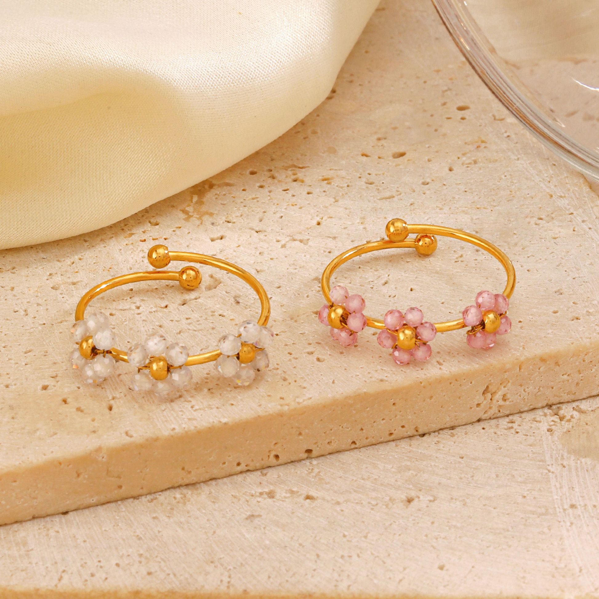 Gold rings with floral designs on a beige surface