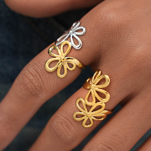 Gold and silver floral earrings on a hand